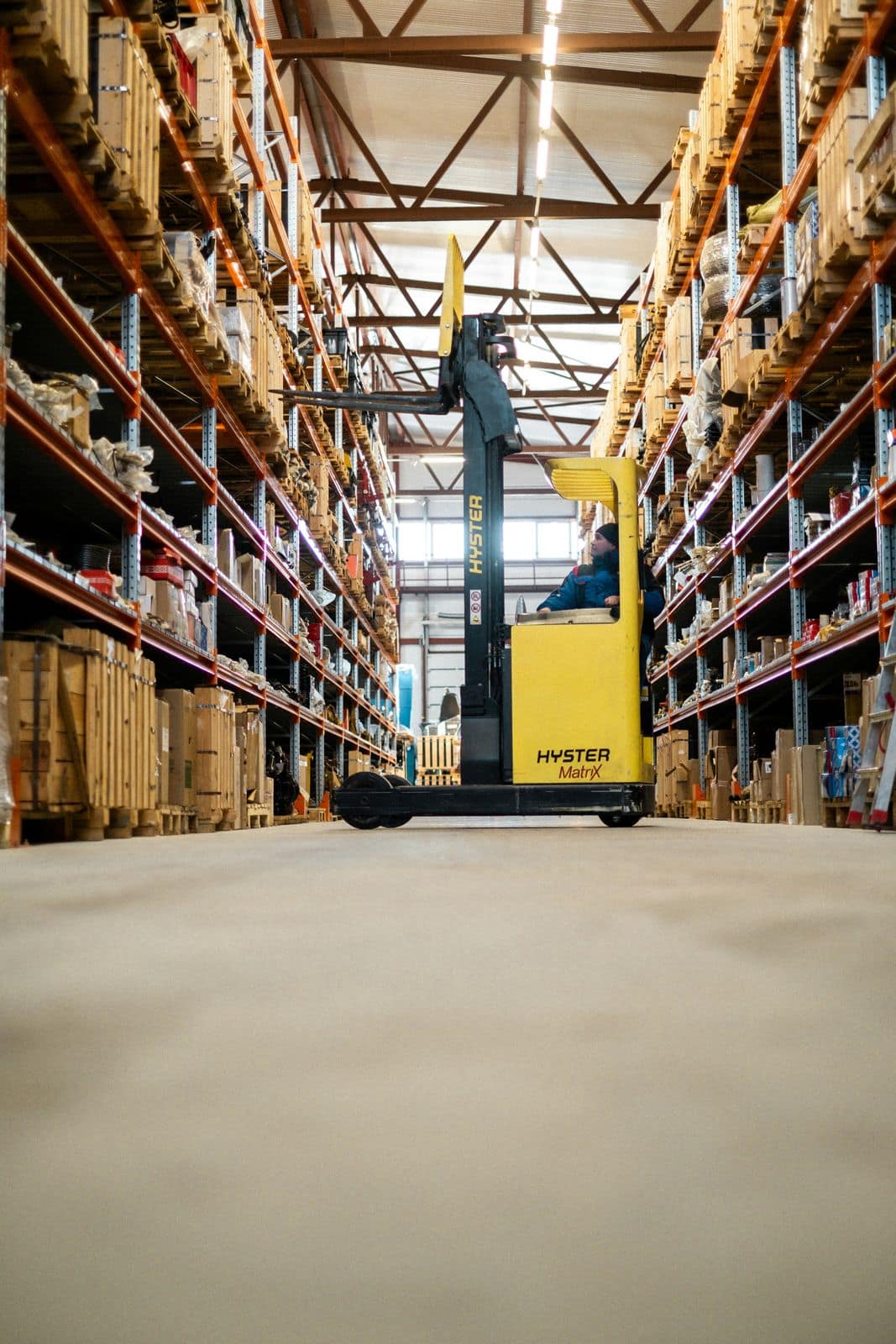 A forklift operator moving pallets in a distribution warehouse aisle